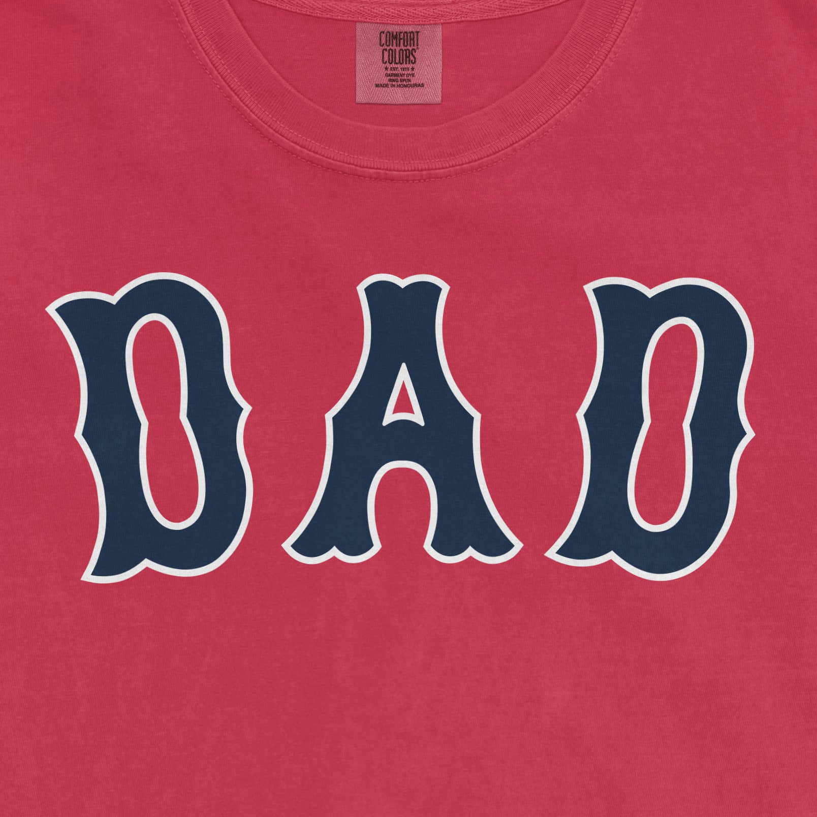 Pink Comfort Colors T-shirt with "DAD" in bold navy blue letters outlined in white, celebrating Boston baseball dads.