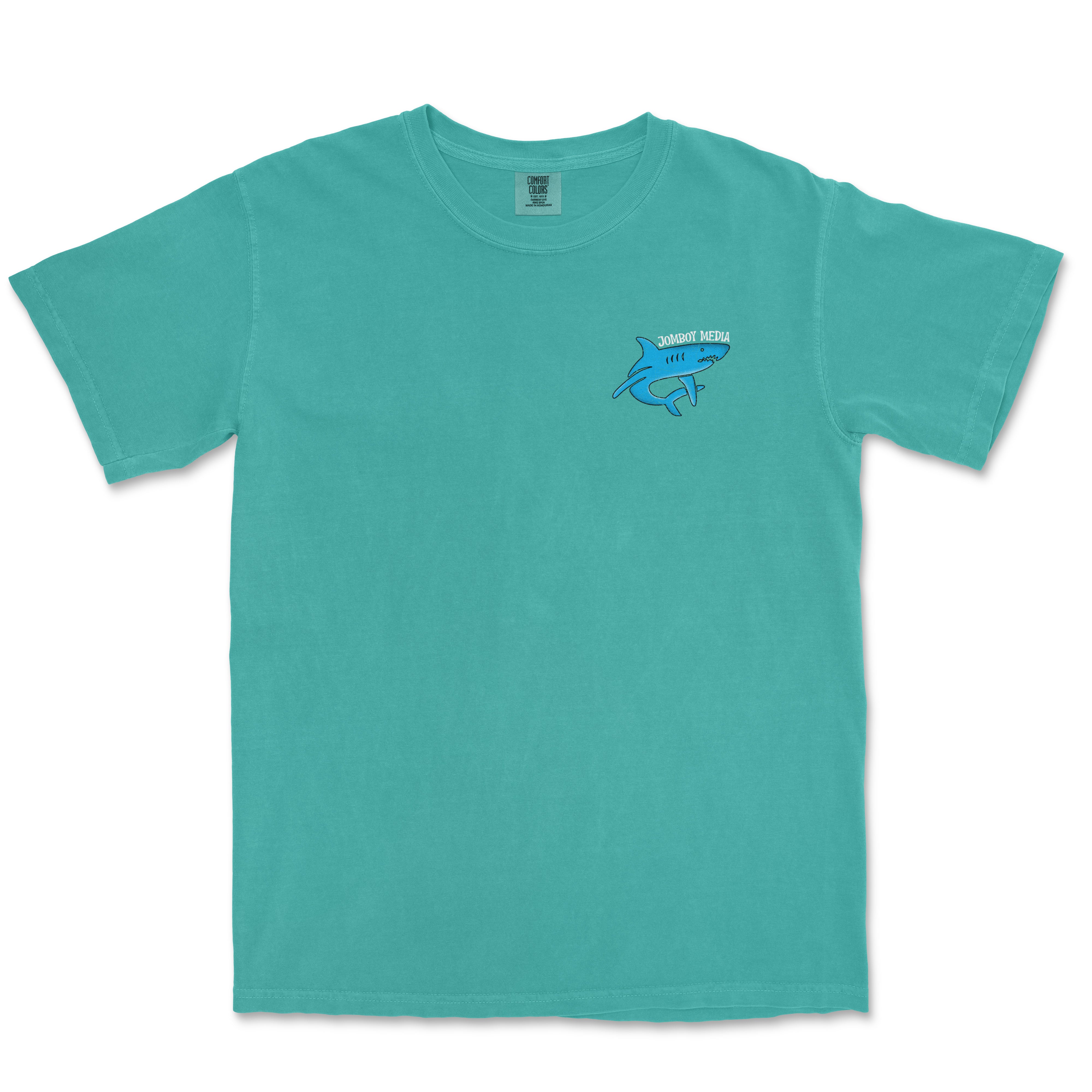 Turquoise Comfort Colors tee featuring a small Jomboy Media shark logo on the chest.