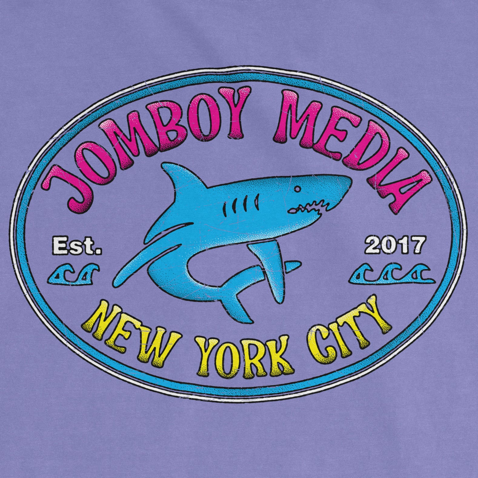 Purple Comfort Colors tee featuring a colorful "Jomboy Media" logo with a shark illustration, "Est. 2017," and "New York City" text.