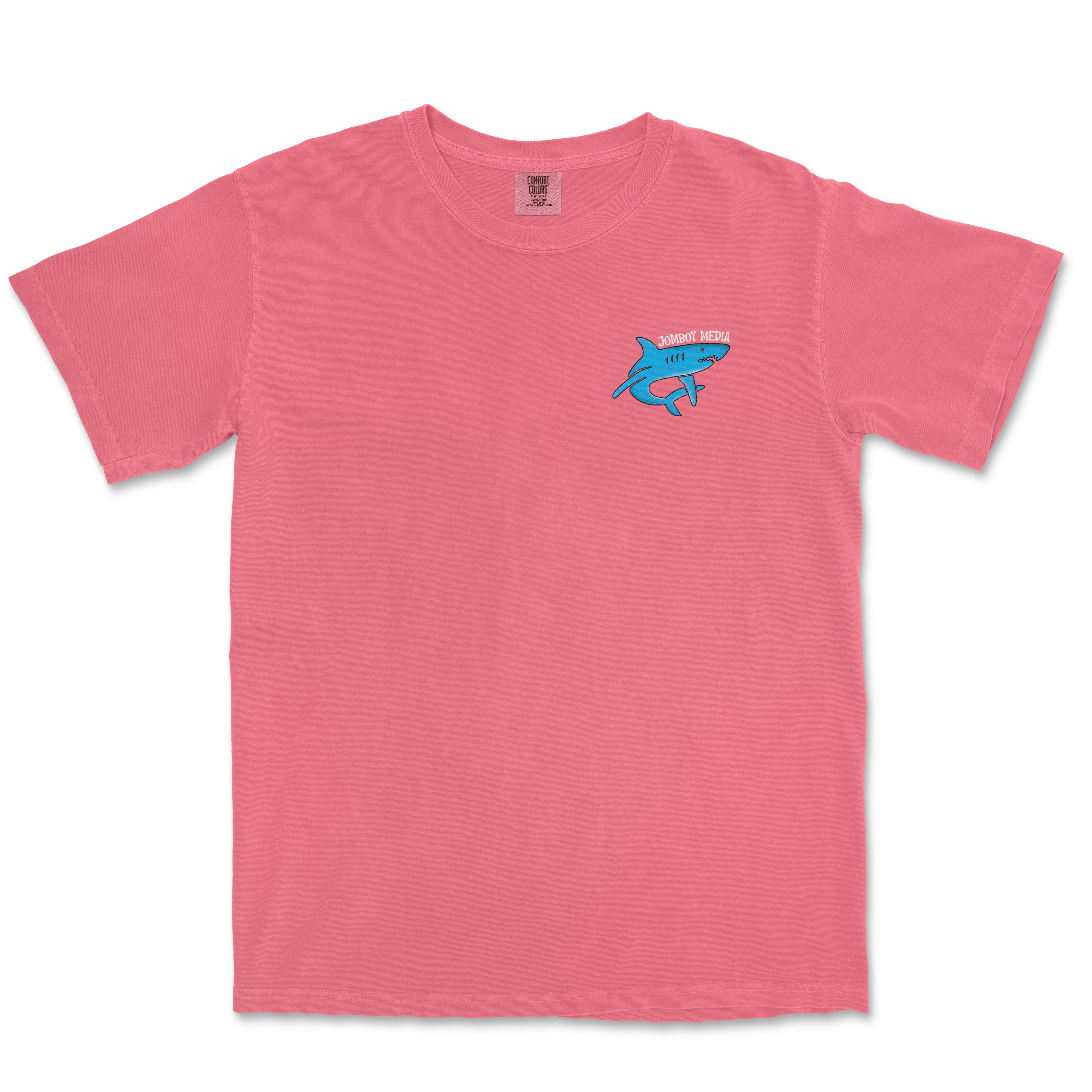 Pink Comfort Colors tee featuring a small blue shark graphic and "Jomboy Media" text on the front chest.