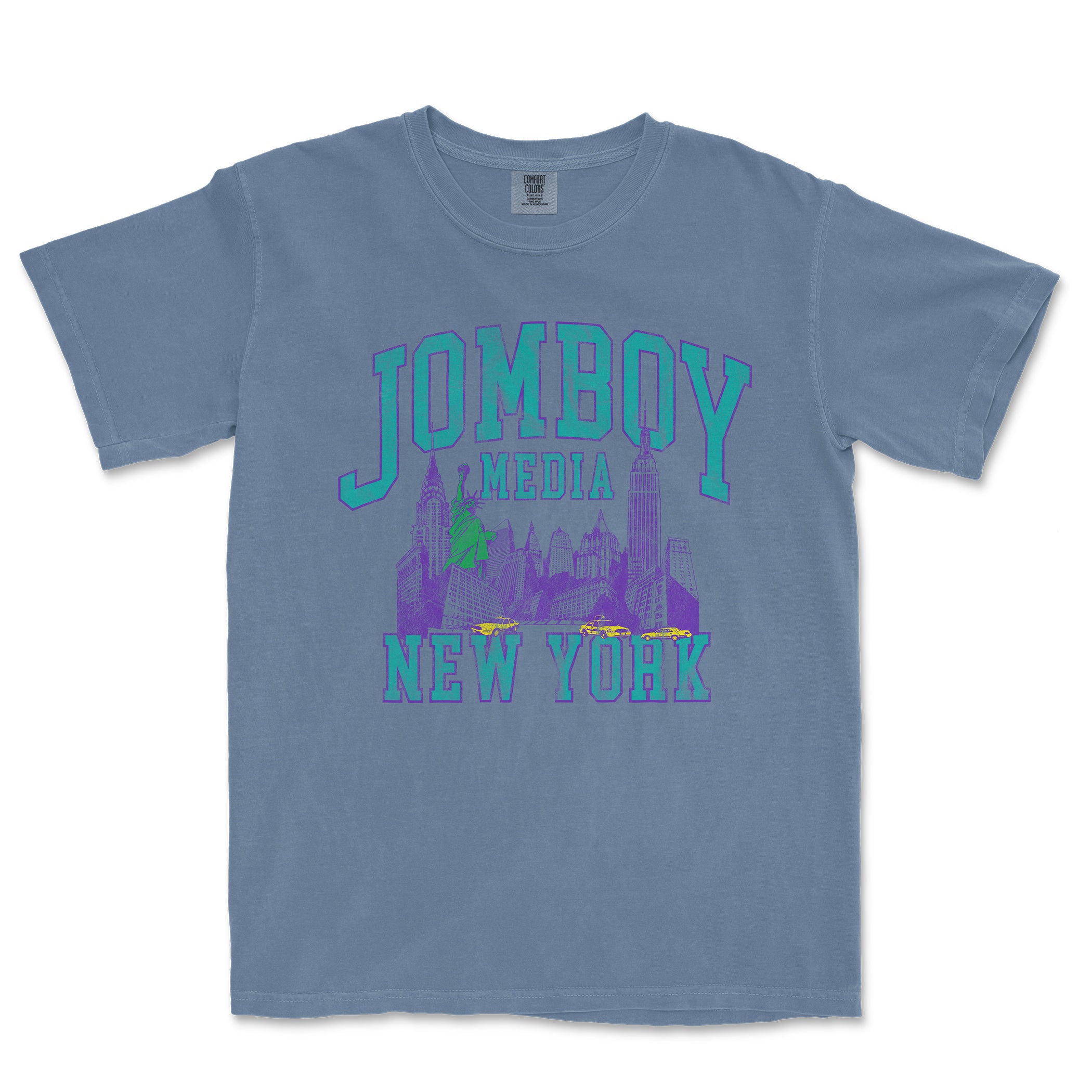 Blue Comfort Colors T-shirt featuring a 90's style graphic design of New York City skyline, "JOMBOY MEDIA" text, and taxis.