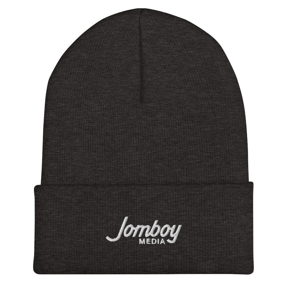 Black beanie hat with "Lomboy Media" embroidered in white on the front fold, designed for warmth and casual style.