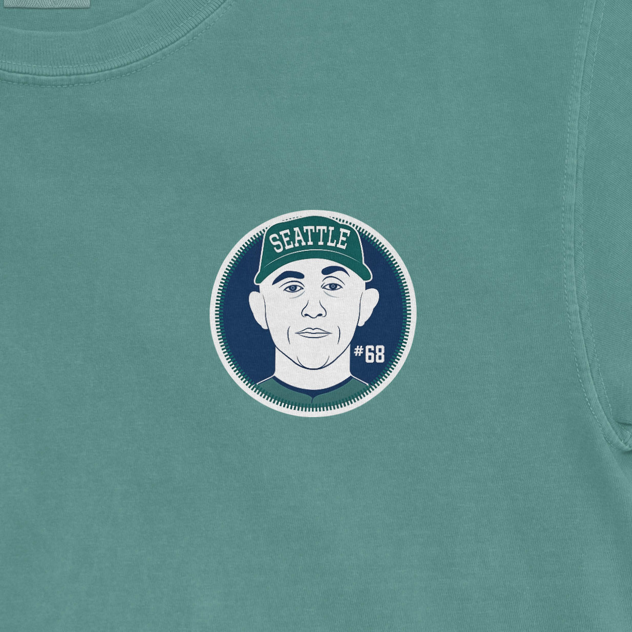 Close-up of a teal Comfort Colors tee featuring a graphic of George Kirby with "Seattle" and "#68" on his cap.
