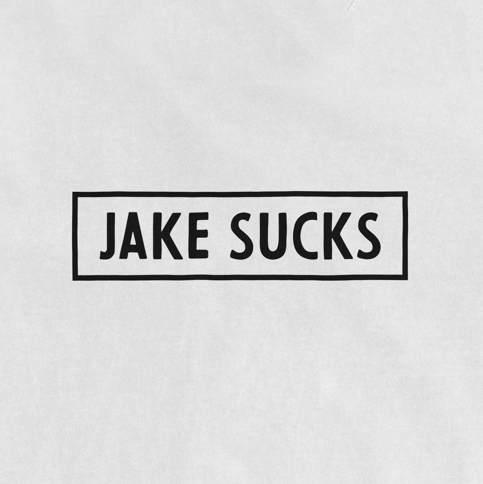 White vintage T-shirt with black text inside a rectangular border that reads "JAKE SUCKS" in bold, uppercase letters.