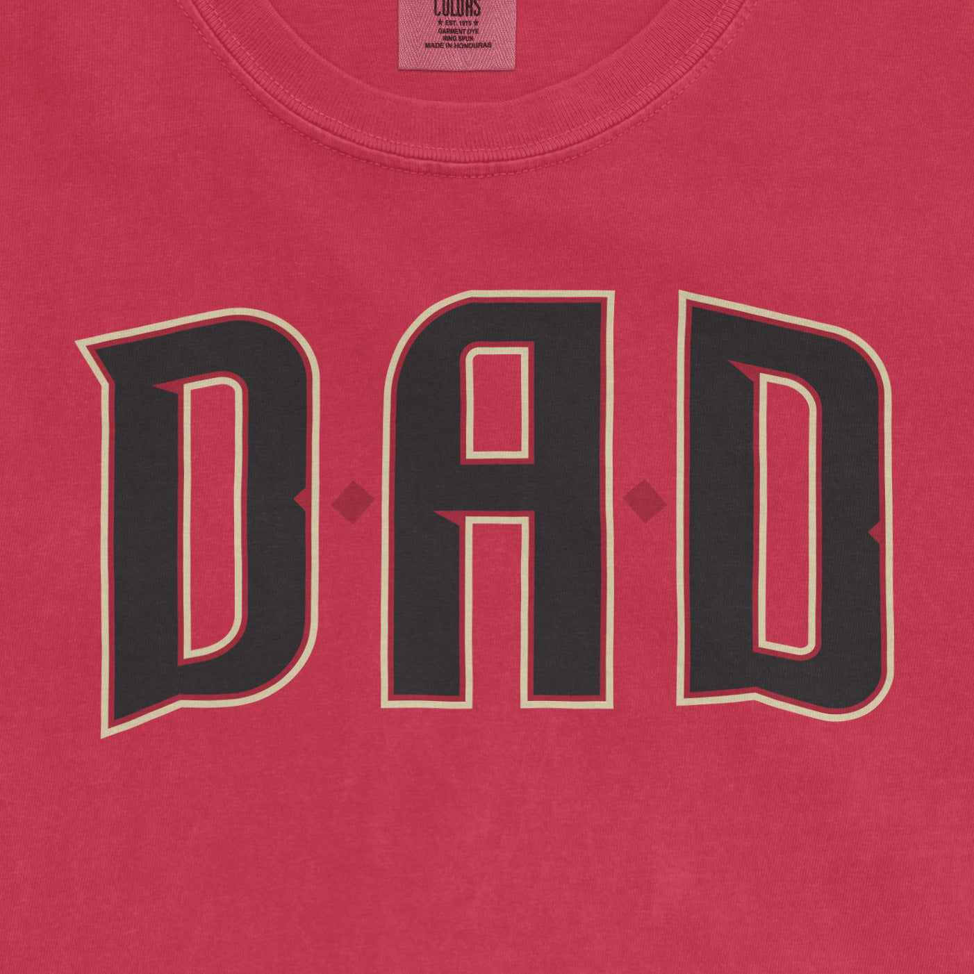 Pink Comfort Colors tee with bold black "DAD" text outlined in white, celebrating Arizona baseball dads.
