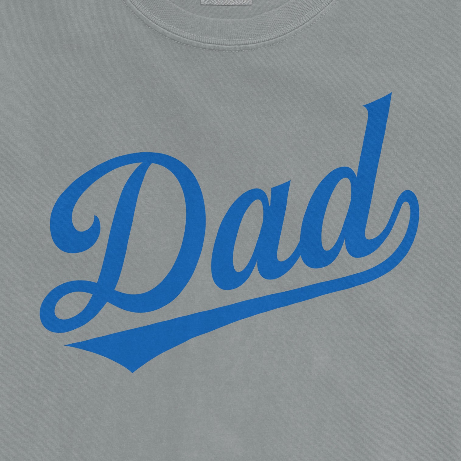 Comfort Colors tee with "Dad" printed in bold blue script on a light gray fabric background.