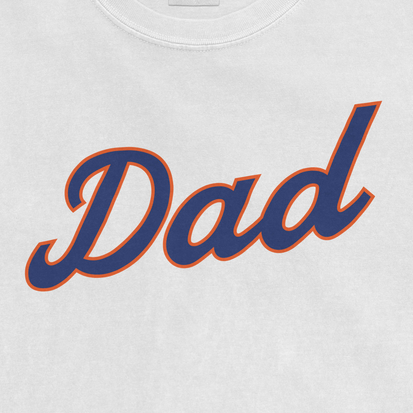 Close-up of a white T-shirt with the word "Dad" in bold navy blue script outlined in orange.