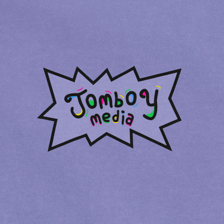 Comfort Colors tee featuring a "Jomboy Media" logo with colorful, playful text inside a black comic-style burst on lavender fabric.