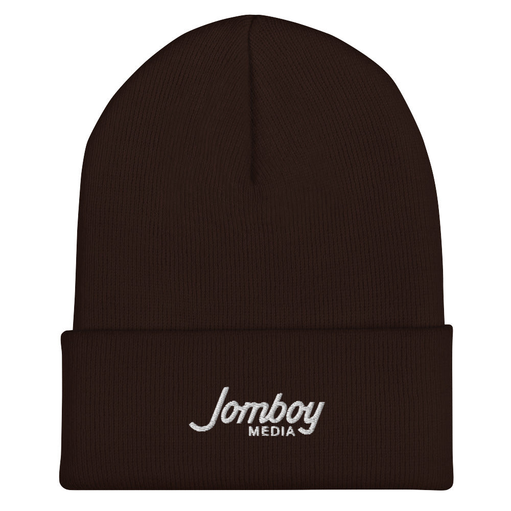 Brown beanie hat with "Jomboy Media" embroidered in white on the front cuff, featuring a folded brim and a snug fit.