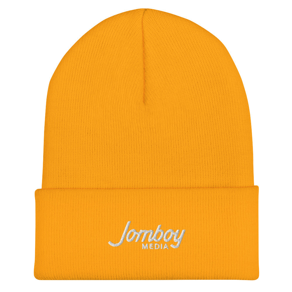 Orange beanie with "Lomboy Media" embroidered in white on the folded cuff, featuring a simple, warm design.