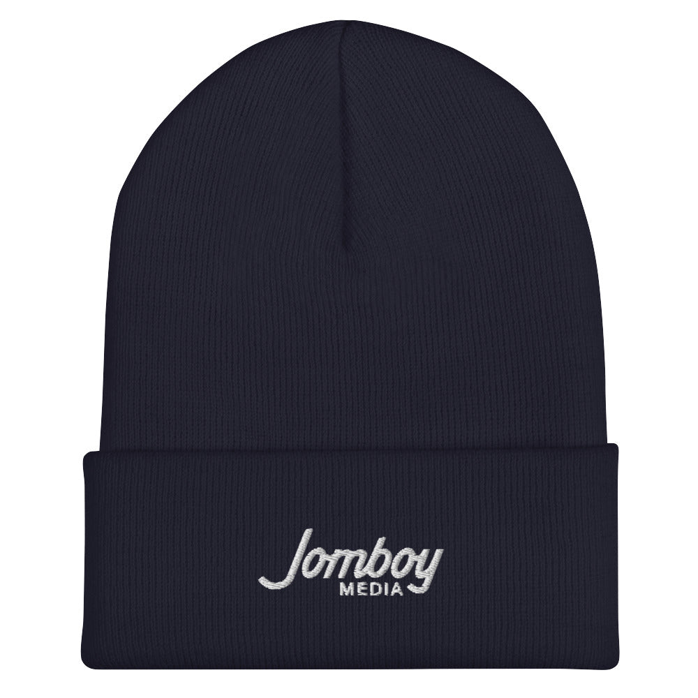 Navy blue beanie with "Jomboy Media" embroidered in white on the front cuff, featuring a folded brim and a knit texture.