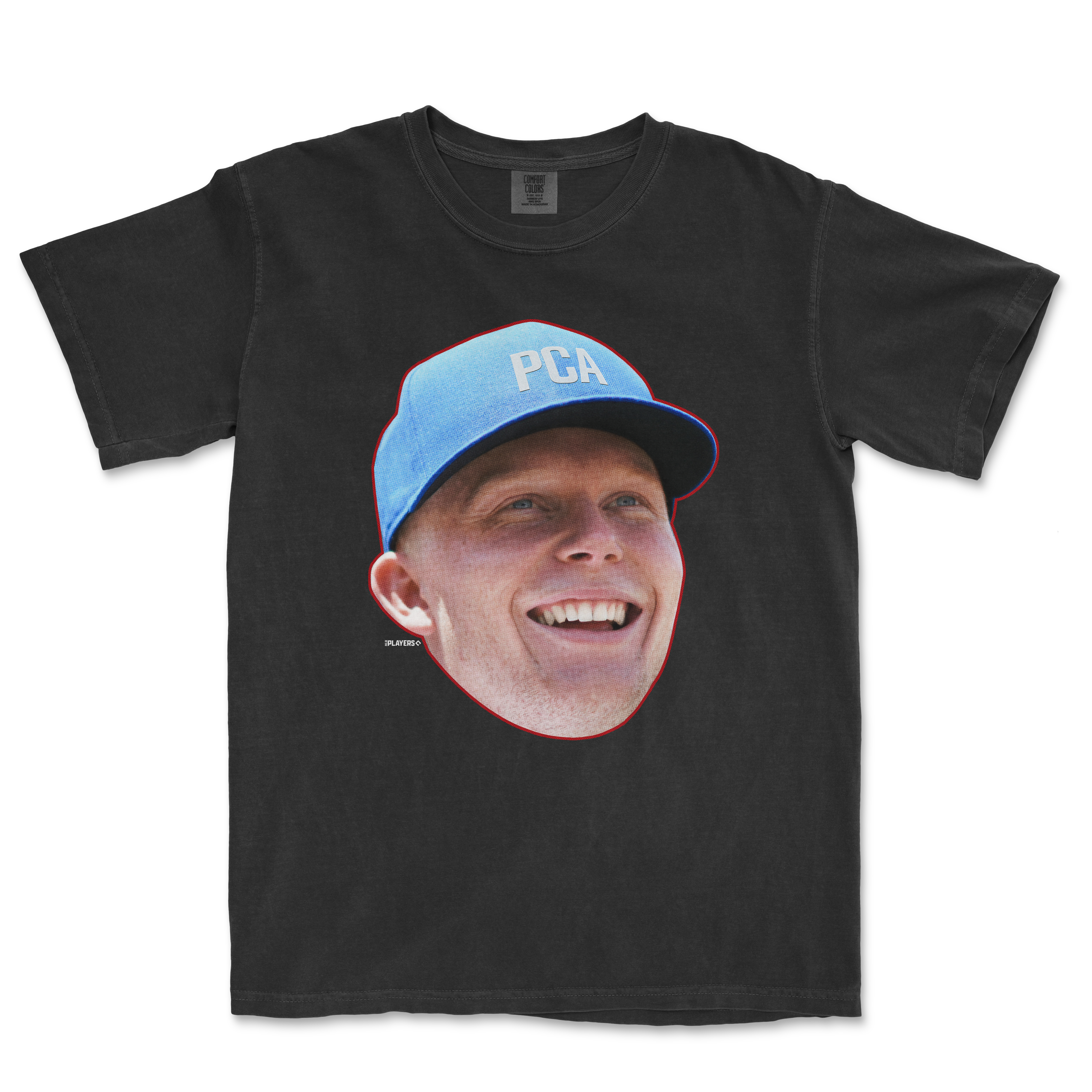 Black t-shirt featuring a large graphic of a smiling person wearing a blue PCA cap, part of the Head in the Game Series.